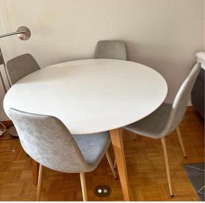 une table blanche entourée de trois chaises grises dans l'établissement L’appartement du père Noël, à Genève