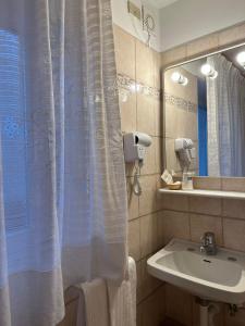 bagno con lavandino e tenda doccia di Hotel Rododendro Val di Fassa a Campitello di Fassa
