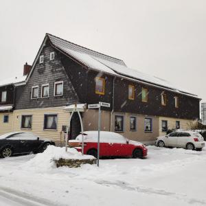 ein Haus mit einem roten Auto im Schnee in der Unterkunft Gästehaus Familie Rinke in Bad Harzburg