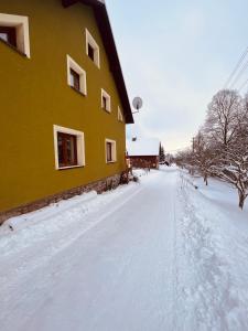 una carretera cubierta de nieve junto a un edificio amarillo en Chalupa U Franze en Malá Morava