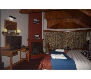 una camera con letto, scrivania e TV di Hotel Aksa Resort, Pahalgam a Pahalgam