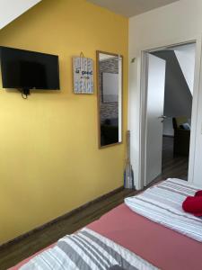 ein Schlafzimmer mit einem Bett und einem Fernseher an der Wand in der Unterkunft Ferienwohnungen Norderney Haus Julianne Wohnung Steuerbord Familie Poppinga in Norderney