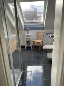 ein Badezimmer mit einem Fenster, einem Waschbecken und einem Stuhl in der Unterkunft Ferienwohnungen Norderney Haus Julianne Wohnung Steuerbord Familie Poppinga in Norderney