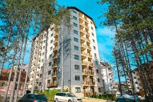 a tall building with cars parked in front of it at Apartman Knez 2 in Zlatibor