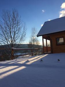 a building with snow on the ground next to a fence at Relaksówka in Roztoka