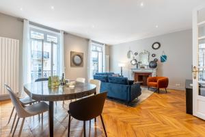 uma sala de estar com uma mesa e um sofá azul em Sweet Inn - Triangle d'Or em Paris