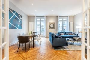 ein Wohnzimmer mit einem blauen Sofa und einem Tisch in der Unterkunft Sweet Inn - Triangle d'Or in Paris