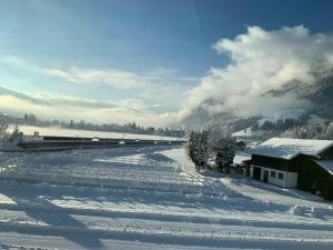 un campo cubierto de nieve con una casa y un tren en Appartement Buchwald, en Maishofen