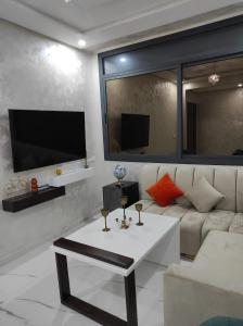ein Wohnzimmer mit einem weißen Sofa und einem TV in der Unterkunft La Joie Al Jadid in Nador