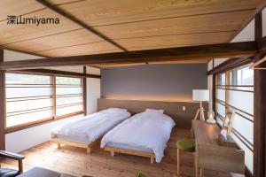 2 camas en una habitación con techos de madera en 深山邸miyama-tei, en Zentsuji