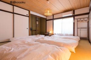 善通寺市にある深山邸miyama-teiの窓付きの客室で、白いベッド2台が備わります。