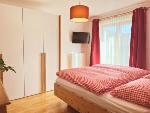 a bedroom with a bed and a window with red curtains at Appartements Skida in Reith bei Kitzbühel