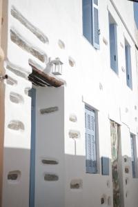 un edificio blanco con persianas y ventanas azules en Elegant white in the heart of Ioulida on the island of Kea, en Ioulida