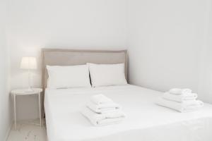Una cama blanca con toallas blancas. en Elegant white in the heart of Ioulida on the island of Kea, en Ioulida