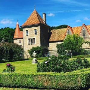 stary dom z pomarańczowym dachem na zielonym dziedzińcu w obiekcie Château de Bournel w mieście Cubry