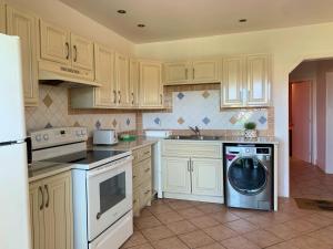 een keuken met witte kasten en een wasmachine bij Jolly Holiday Apartment in Saint Mary
