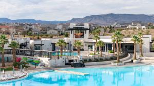 a large pool with palm trees and buildings at The Pearl at Desert Shores townhouse in St. George
