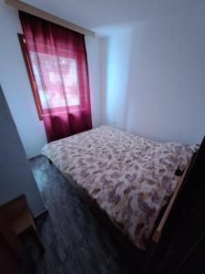 Cama en habitación con ventana roja en Apartmani "DA HOX" Vlašić 2 en Vlasic