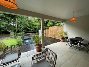 patio con sillas y mesa y vistas a la piscina en Villa Les Jardins de la Trinité en Saint-Philippe