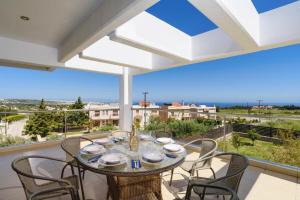 une salle à manger avec une table et des chaises sur un balcon dans l'établissement Villa Cleopatra Private Heated Pool, Tennis & Football, à Koskinou