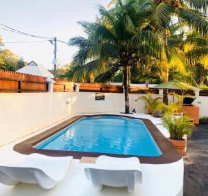 a swimming pool in a backyard with two white chairs at Sonnige Ferienwohnung mit Wifi in Flic-en-Flac