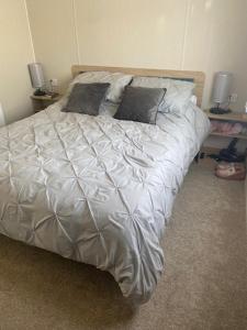Una cama con sábanas blancas y almohadas en un dormitorio en Duffy's Den - Parkdean California Cliffs - Fulmar 45, en Scratby