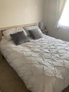 ein weißes Bett mit zwei Kissen darauf im Schlafzimmer in der Unterkunft Duffy's Den - Parkdean California Cliffs - Fulmar 45 in Scratby