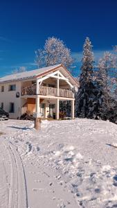une maison dans la neige avec des empreintes de pied dans la neige dans l'établissement Gîte des Roches, à La Chaux-du-Dombief