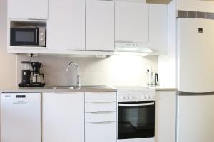 Una cocina blanca con fregadero y microondas. en Suite Apartment KIELO in Center near all the main spots, WiFi, en Rovaniemi 21 fotos más