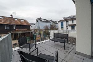 a patio with chairs and a bench on a balcony at 3.5 Room Apartment in Würenlos