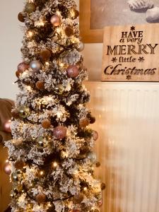 Un árbol de Navidad con un signo de Navidad feliz en Maria’s Home, en Pireo