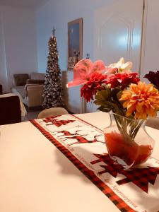 Maria’s Home في بيرايوس: طاولة مع إناء من الزهور وشجرة عيد الميلاد