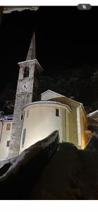 uma igreja com uma torre de relógio à noite em Ca del Nore em Fontainemore