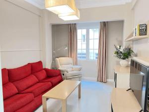 een woonkamer met een rode bank en een stoel bij Magnifico Alojamiento Con Encanto En El Centro in Santander