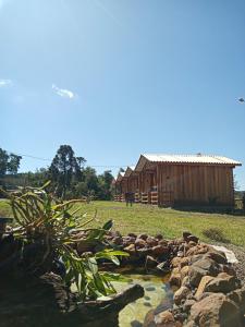 uma cabana de madeira e um lago em frente a um edifício em Hotel cabanas bom Jesus em Ametista do Sul