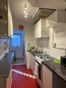 a kitchen with white cabinets and a red tile floor at Double Room With Free WiFi Keedonwood Road in Bromley