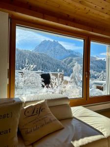 ein großes Fenster mit Blick auf einen verschneiten Berg in der Unterkunft Chasa Stefania mit rundum Bergblick und Garten in Scuol