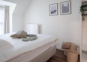 a white bedroom with a bed with white sheets at Belcoast Guesthouse in Middelkerke