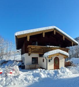 Cabaña de madera con nieve en el suelo en Ferienhaus Sommerbichl, en Zell am See