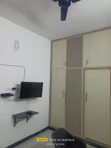 uma sala de estar com televisão e uma parede com armários em LA villa Rani em Madurai