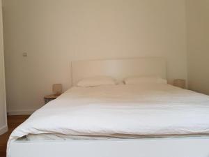 Cama blanca con sábanas y almohadas blancas en Sleepin Orléans - Parking - Netflix en Orléans