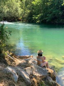 a woman sitting on a rock near a river at Gite au coeur de la nature 