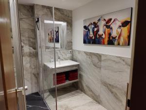 La salle de bains est pourvue d'un lavabo et d'une peinture de vaches. dans l'établissement Apartment Reiter, à Zellbergeben