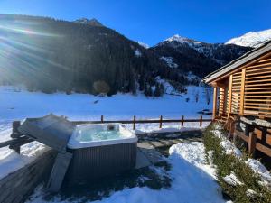 uma banheira de hidromassagem na neve ao lado de uma cabana em De Goldene Traum em Gressoney-Saint-Jean