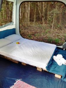 una cama en la parte trasera de una caravana con una ventana en YbYmara Eco Glamping en Serra Grande