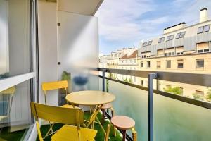 a balcony with yellow chairs and a table and a window at Soleil du canal Saint Martin in Paris