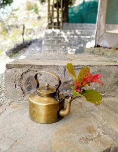 a brass tea pot with a flower on a rock at Pinwheel Retreat in Lansdowne