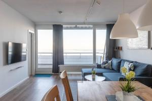 Una sala de estar con un sofá azul y una mesa. en Ferienwohnung Pier 1167, en Schilksee