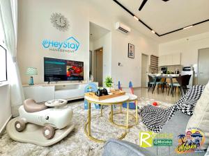 uma sala de estar com uma televisão e uma sala de estar com um sofá em Amber Cove Impression City By Heystay Management em Malaca