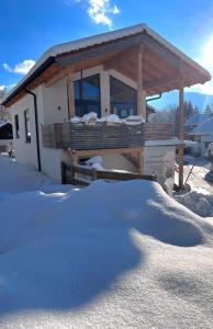una casa con una gran pila de nieve delante de ella en Fuxbau Waldlounge en Ruhpolding